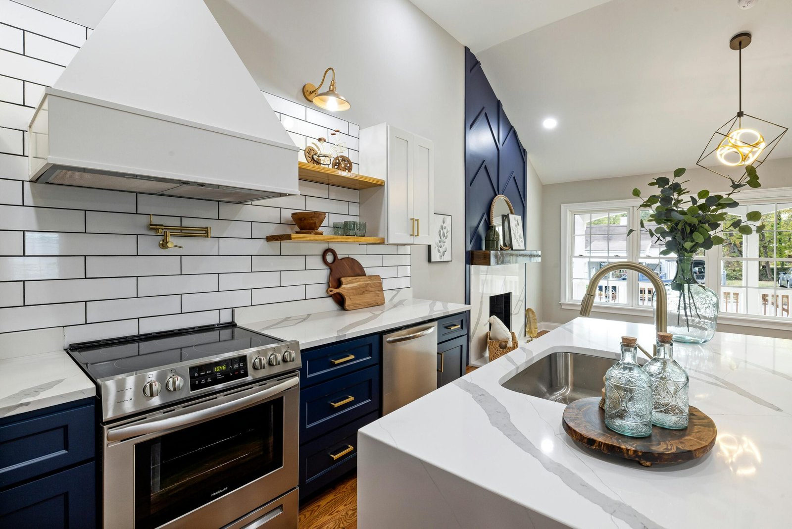 A modern kitchen featuring marble countertops, a stainless steel stove, and elegant blue cabinets.